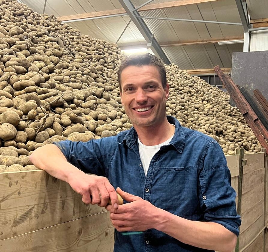 Glücklicher Landwirt neben Kartoffelernte