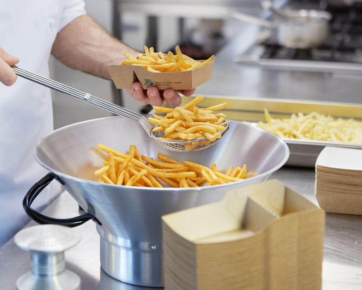 Pommes die fettfrei frittiert wurden werden aus einer schale in verpackung gehoben