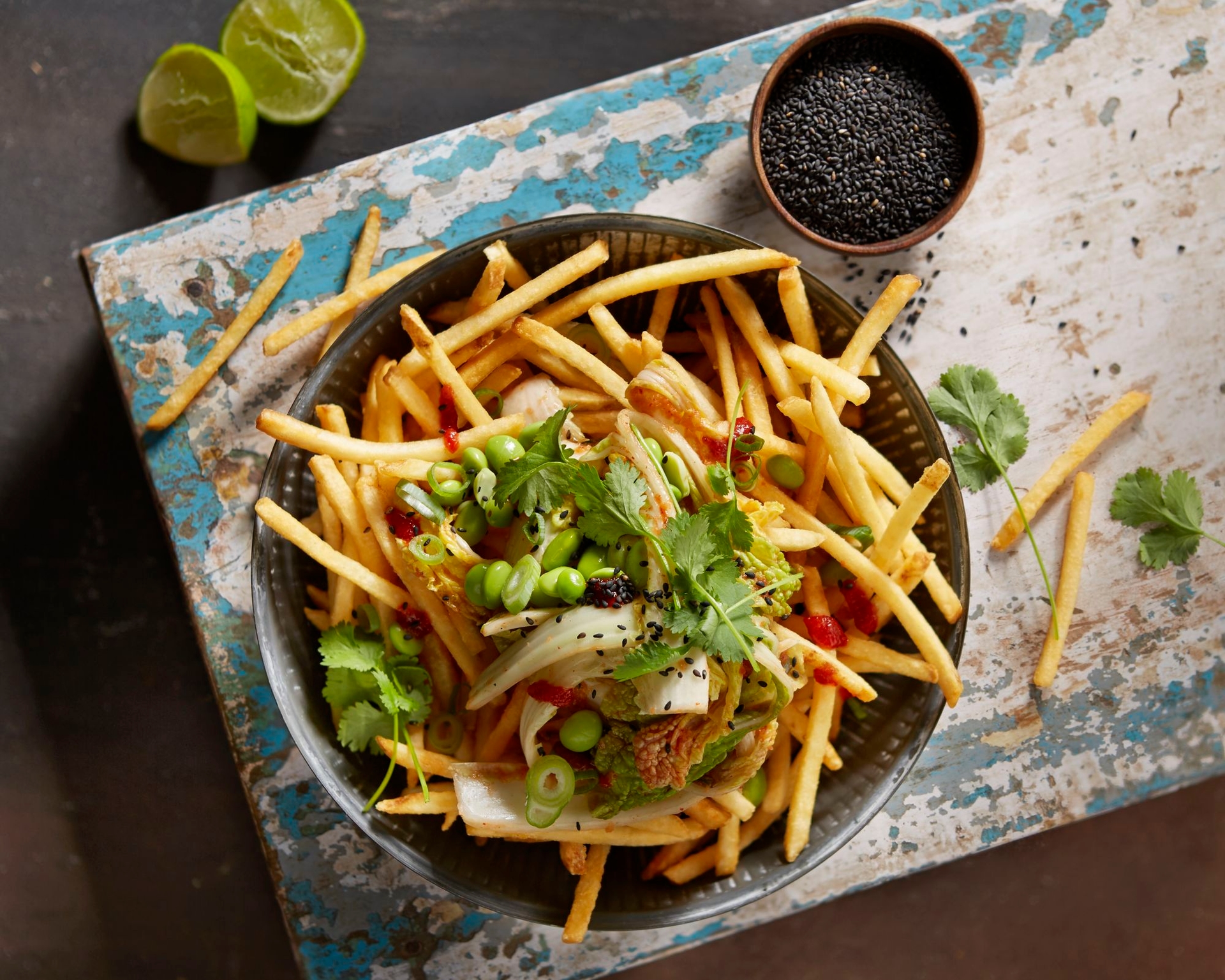 Pommes aus der Heissluftfritteuse serviert mit Toppings auf Holzbrett von oben fotografiert